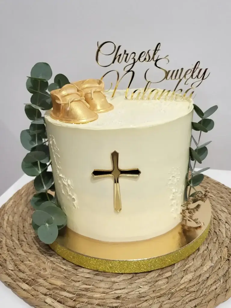 Tort z okazji Chrztu Świętego Natanka ozdobiony gałązkami eukaliptusa, dwoma złotymi toperami oraz bucikami z masy cukrowej pomalowanymi na złoto
