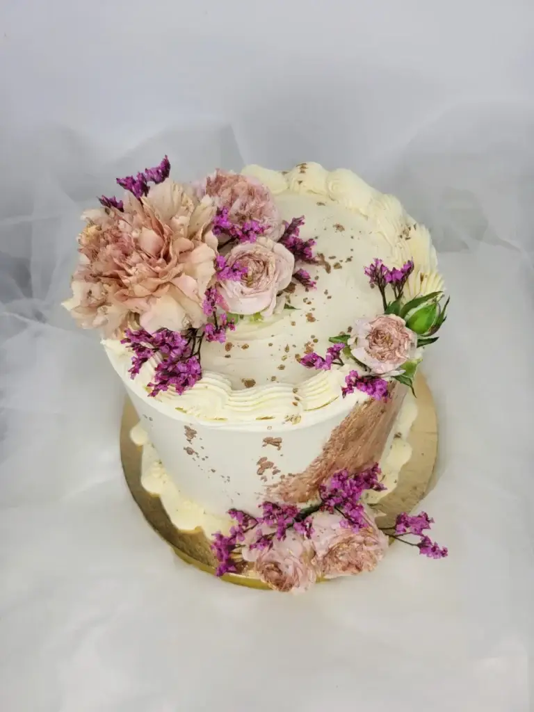 Romantyczny tort z kwiatami w pastelowych odcieniach, złotymi akcentami i kremowymi zdobieniami
